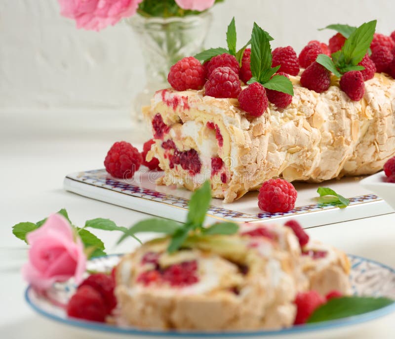 Baked Meringue Roll with Cream and Fresh Fruits on a White Wooden Board