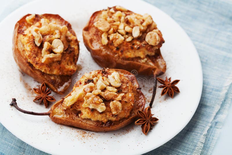 Baked pears with ricotta, walnuts, honey and cinnamon in a white plate on blue background. Delicious autumn dessert. royalty free stock photo Baked pears with ricotta, walnuts, honey and cinnamon in a white plate on blue background. Delicious autumn dessert. royalty free stock photo
