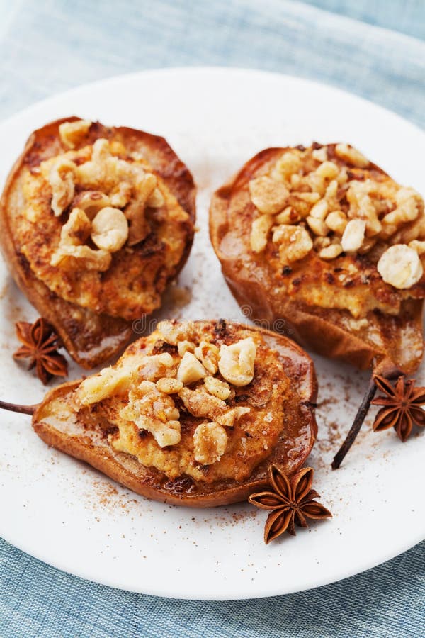 Baked pears with ricotta, walnuts, honey and cinnamon in a white plate on blue cloth background. Delicious autumn dessert. royalty free stock photo Baked pears with ricotta, walnuts, honey and cinnamon in a white plate on blue cloth background. Delicious autumn dessert. royalty free stock photo