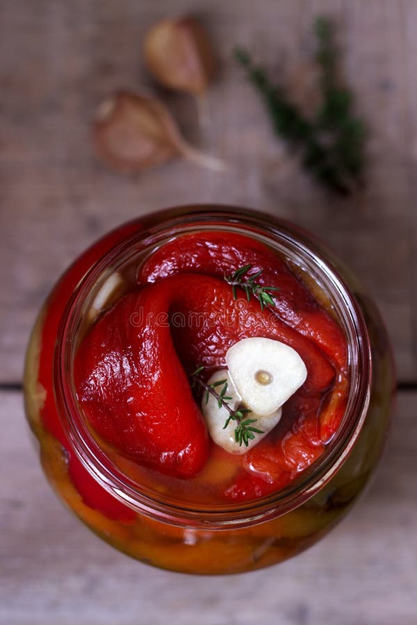 Baked pickled sweet pepper with garlic and thyme in a glass jar.