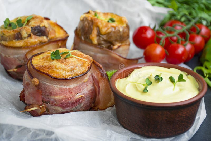 Baked Potatoes with Cheese Wrapped in Bacon on a Dark Table. Closeup