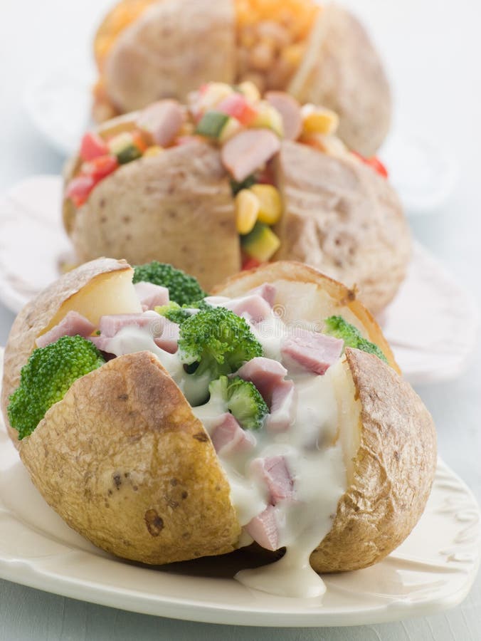 Three baked Potatoes with a Selection of Toppings stock photography.