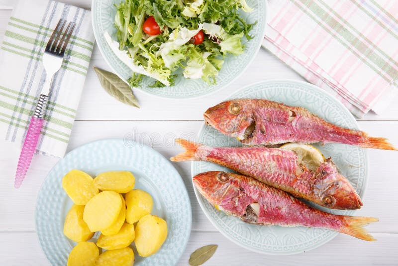 Baked red mullet served with boiled potatoes and green salad