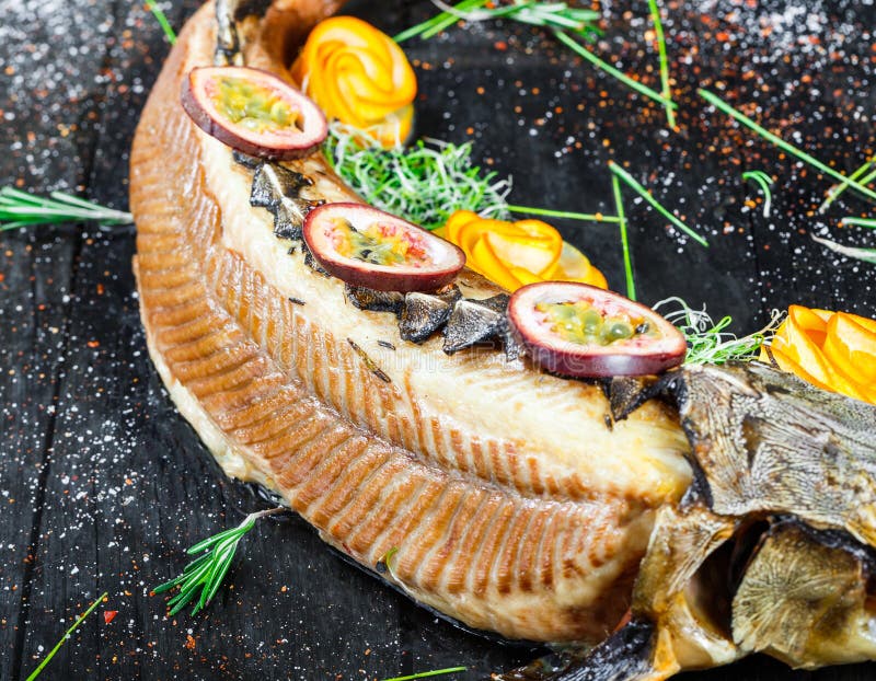 Baked sturgeon fish with rosemary, lemon and passion fruit on plate on wooden background close up. royalty free stock photography Baked sturgeon fish with rosemary, lemon and passion fruit on plate on wooden background close up. royalty free stock photography