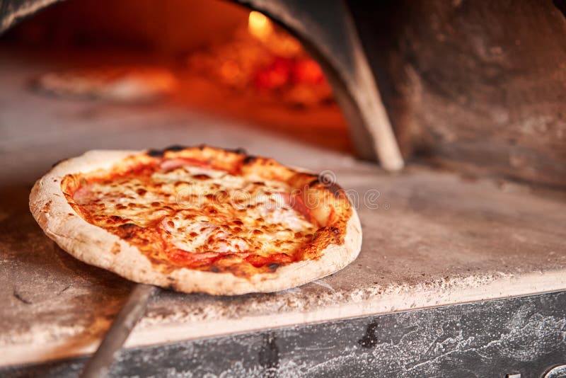 Baked tasty margherita pizza in Traditional wood oven in Naples restaurant, Italy. Original neapolitan pizza. Red hot coal. Baked tasty margherita pizza in Traditional wood oven in Naples restaurant, Italy. Original neapolitan pizza. Red hot coal