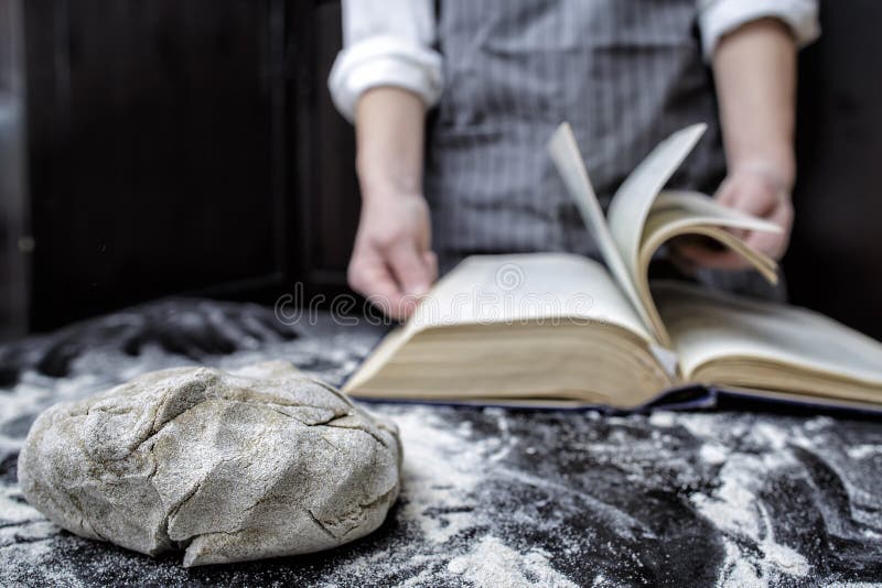 Baker chef-kok die een recept in een kookboek zoeken stock fotografie Baker chef-kok die een recept in een kookboek zoeken stock fotografie