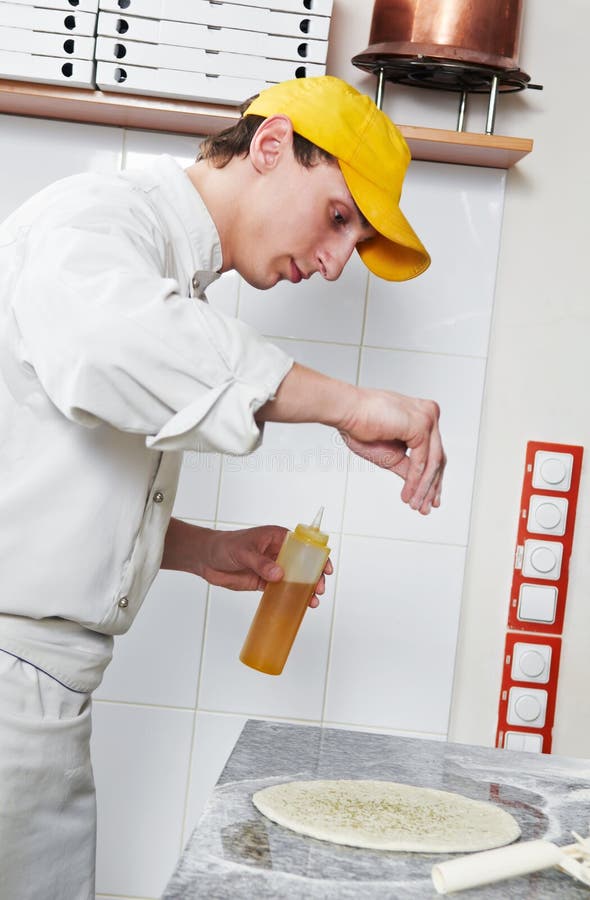 One chef baker in white uniform making bakery dough for pizza at kitchen. One chef baker in white uniform making bakery dough for pizza at kitchen