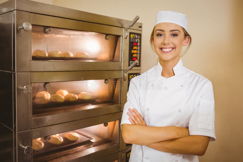 Baker smiling at camera beside oven. 