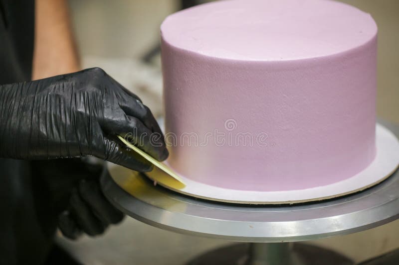 Baker Wearing Protective Gloves Decorating a Beautiful Purple Cake in