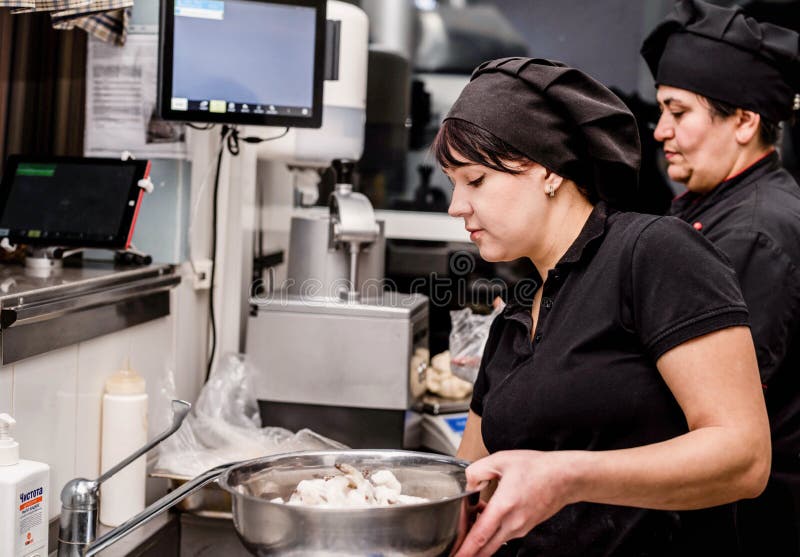 Bakers in Black Uniform at the Pizzeria Kitchen Working on Order Stock