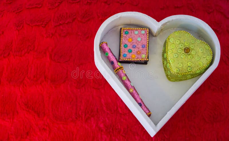 Bakgrund för valentindaggarneringar, en vit hjärta formade asken med en penna, en anmärkningsbok och en hjärta formad ask som läg arkivfoton Bakgrund för valentindaggarneringar, en vit hjärta formade asken med en penna, en anmärkningsbok och en hjärta formad ask som läg arkivfoton