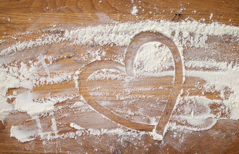 Baking background with heart shape and flour on a dark table. Copy space for text