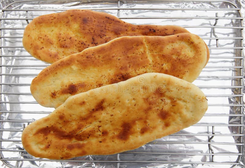 Homemade Indian naan bread cooling on a rack. Homemade Indian naan bread cooling on a rack