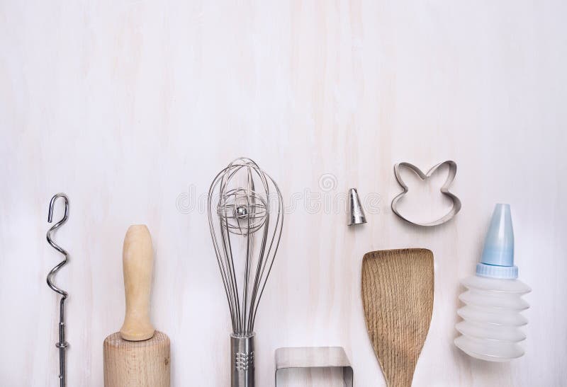 Baking set utensils with rolling pin, spatula, whisk, slotted wooden spoon on white wooden background, top view