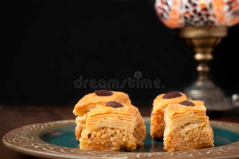 Baklava pieces served on a rustic plate. Baklava is a popular sweet in the Middle East made from many layers of filo pastry and filled with nuts soaked in syrup.