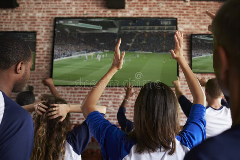 Bakre sikt av besvikna vänner som håller ögonen på leken i sportstång royaltyfri foto Bakre sikt av besvikna vänner som håller ögonen på leken i sportstång royaltyfri foto