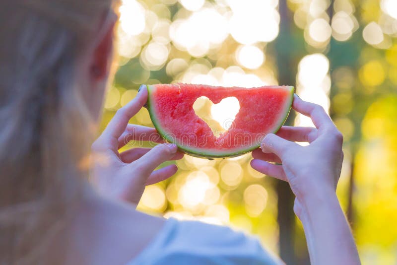Bakre sikt av den kvinnliga hållande vattenmelon med hjärtaformhålet i natur royaltyfria foton Bakre sikt av den kvinnliga hållande vattenmelon med hjärtaformhålet i natur royaltyfria foton