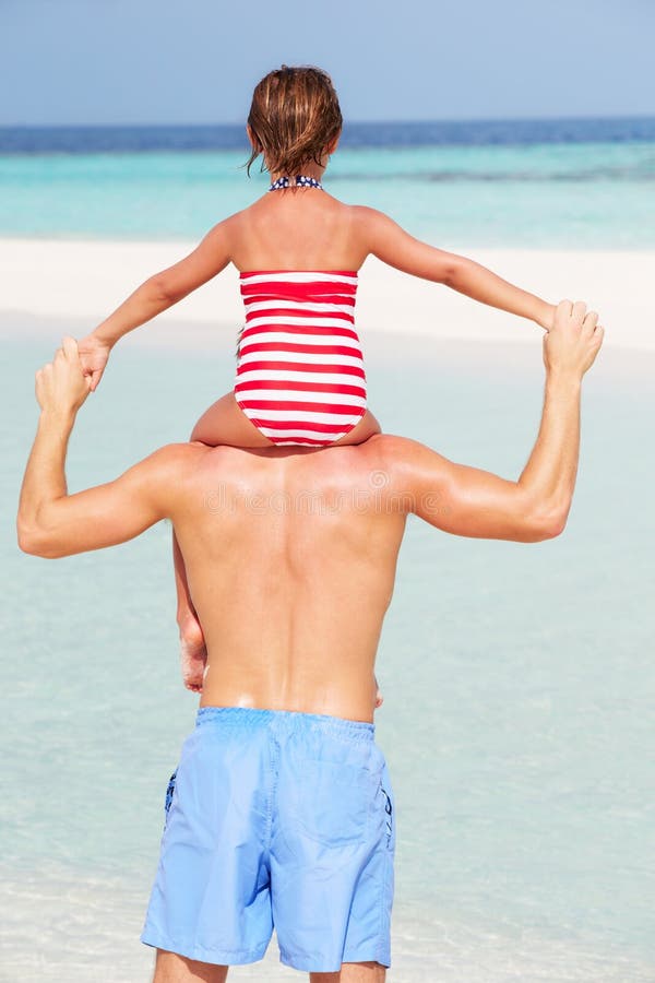 Bakre sikt av ferie för faderCarrying Daughter On strand fotografering för bildbyråer