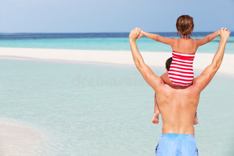 Bakre sikt av ferie för faderCarrying Daughter On strand royaltyfri foto
