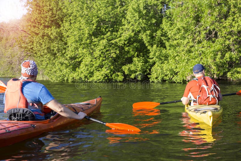 Bakre sikt av mannen som paddlar kajaken i sjön med kvinnan i bakgrund Koppla ihop kayaking i sjön på en solig dag arkivfoton Bakre sikt av mannen som paddlar kajaken i sjön med kvinnan i bakgrund Koppla ihop kayaking i sjön på en solig dag arkivfoton