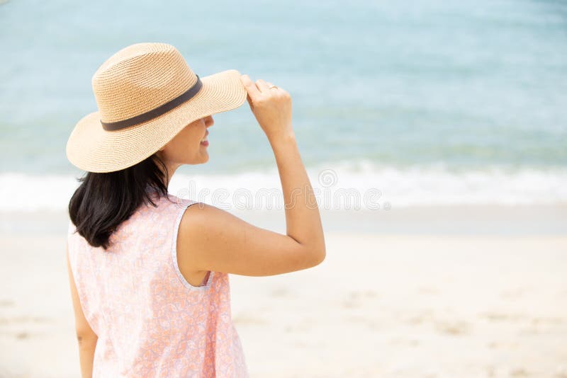 Baksida av vacker kvinna som bär hatt på stranden arkivbild