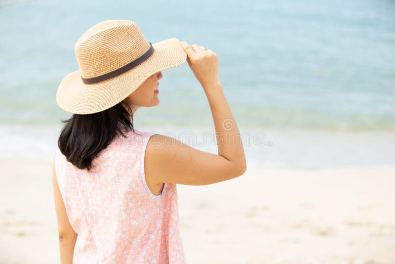 Baksida av vacker kvinna som bär hatt på stranden arkivfoton