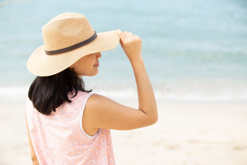 Baksida av vacker kvinna som bär hatt på stranden arkivfoton