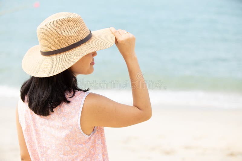 Baksida av vacker kvinna som bär hatt på stranden arkivbilder