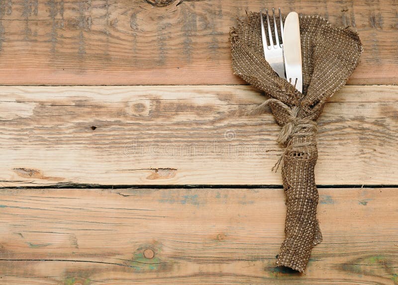 Knife and fork in rough old sacking over wood. Knife and fork in rough old sacking over wood