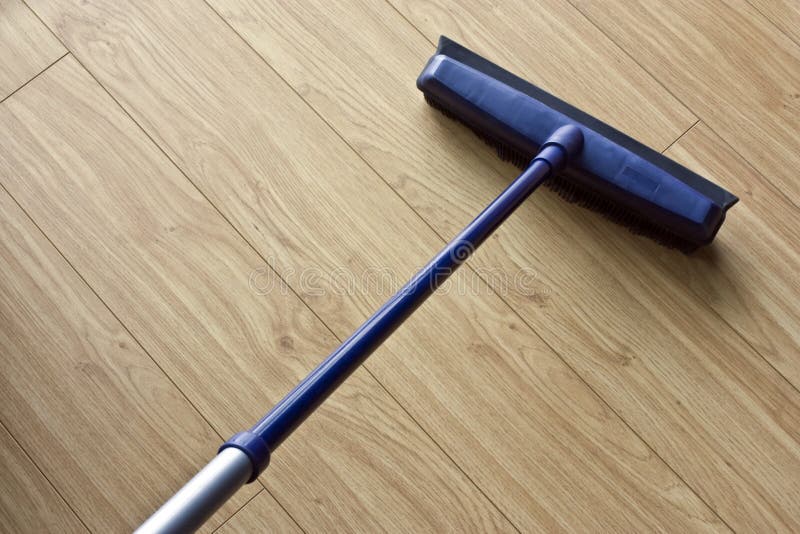 A new brush with an extending handle cleaning a laminate floor. A new brush with an extending handle cleaning a laminate floor.