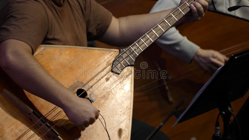 Balalaika wooden in the hands of the musician. Folk musical art of the rural traditional. Man plays the Balalaika. Contrabass stock photography Balalaika wooden in the hands of the musician. Folk musical art of the rural traditional. Man plays the Balalaika. Contrabass stock photography