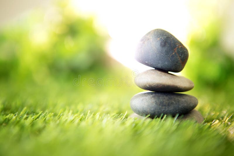 Balance with a pyramid of stone on fresh nature green grass , spa meditation or well-being with zen concept royalty free stock photography Balance with a pyramid of stone on fresh nature green grass , spa meditation or well-being with zen concept royalty free stock photography