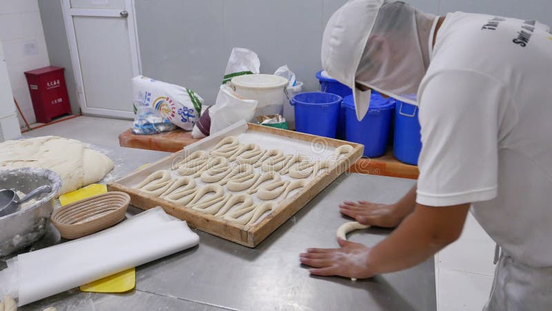 Balanceo del trabajador de la panadería y pasta el formar para los pretzeles