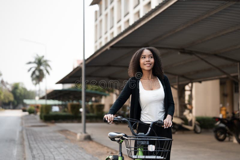 Balans och anslutning. En ung kvinna med sin gröna cykel som förkroppsligar ett harmoniskt förhållande till stadslivet och fotografering för bildbyråer