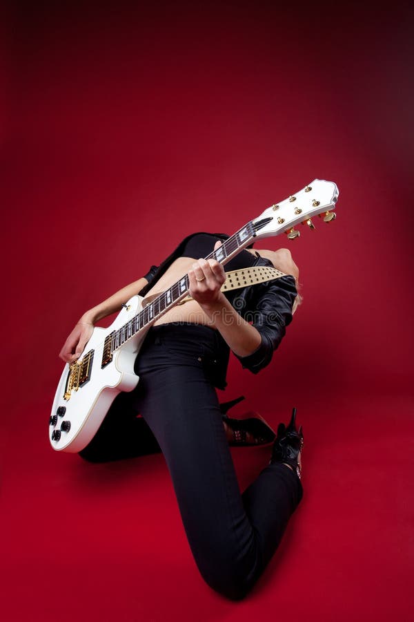 Balanç a mulher no couro preto na guitarra vermelha do jogo imagem de stock Balanç a mulher no couro preto na guitarra vermelha do jogo imagem de stock
