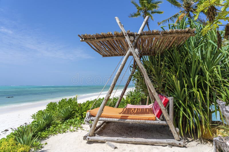 Wooden swing with a mattress under a canopy on the tropical beach near sea, island Zanzibar, Tanzania, East Africa, travel and vacation concept. Wooden swing with a mattress under a canopy on the tropical beach near sea, island Zanzibar, Tanzania, East Africa, travel and vacation concept