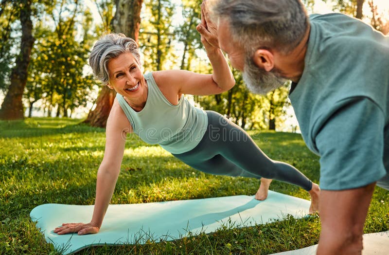Balanță plank. O doamnă cu părul mare și radiant, care stă pe scândură cu brațul întins și îi dă 5 la sută soțului. Om determinat stock photo