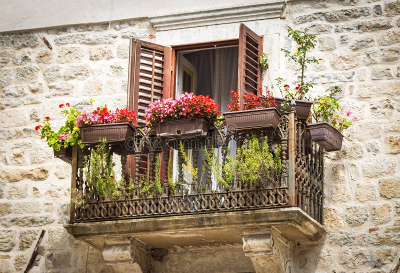 Balcón hermoso del vintage con las verjas a cielo abierto del metal, adornadas con las flores rojas en Kotor, Montenegro imagen de archivo Balcón hermoso del vintage con las verjas a cielo abierto del metal, adornadas con las flores rojas en Kotor, Montenegro imagen de archivo