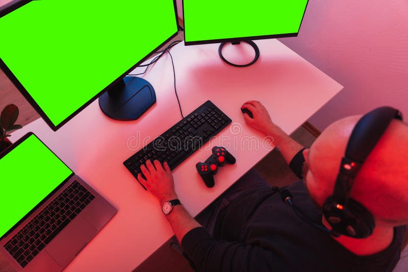 Bald Man is Sitting and Playing in Front of Three Green Screen