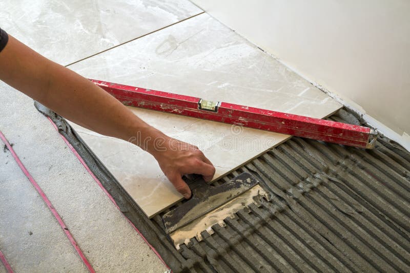 Baldosas cerámicas y herramientas para el solador Mano del trabajador que instala las baldosas Mejoras para el hogar, renovación imagen de archivo Baldosas cerámicas y herramientas para el solador Mano del trabajador que instala las baldosas Mejoras para el hogar, renovación imagen de archivo