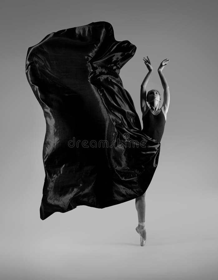 Ballerina in a flying black dress and pointe shoes on a gray background. Ballerina in a flying black dress and pointe shoes on a gray background