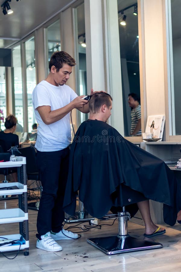 BALI, INDONESIA - 2 GIUGNO 2017: Stilista di capelli al negozio di barbiere sull'isola di Bali fotografia stock BALI, INDONESIA - 2 GIUGNO 2017: Stilista di capelli al negozio di barbiere sull'isola di Bali fotografia stock