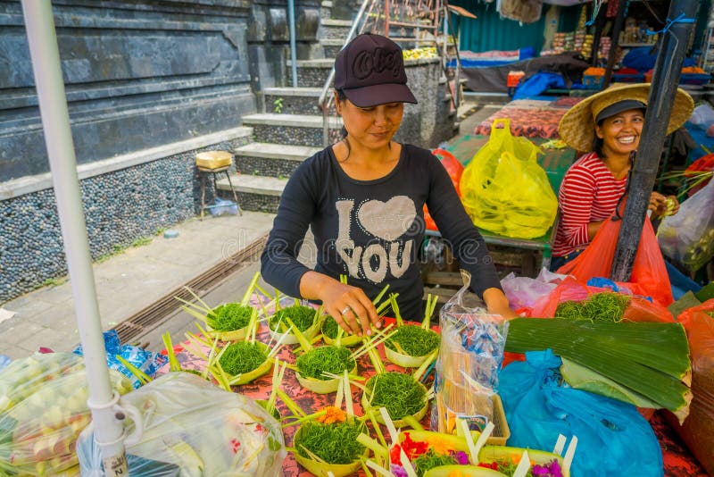 BALI, INDONESIA - MARCH 08, 2017: Unidentified woman do an arrangement of flowers inside of a box made of leafs in a stock image BALI, INDONESIA - MARCH 08, 2017: Unidentified woman do an arrangement of flowers inside of a box made of leafs in a stock image
