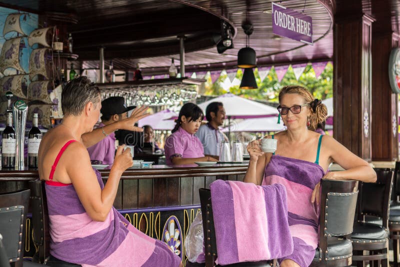 BALI, INDONESIA - MAY 5, 2017: Two women drinking coffe and relaxing in swimming pool bar and restaraunt. Bali.