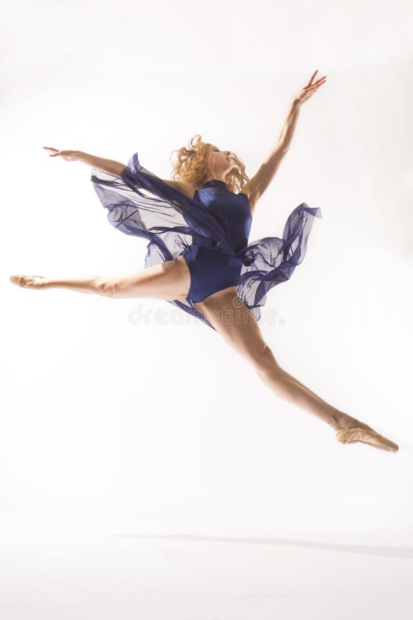 Young woman ballet dancer in pointe shoes,blue leotard and skirt, leaping in the studio against a white background. Young woman ballet dancer in pointe shoes,blue leotard and skirt, leaping in the studio against a white background