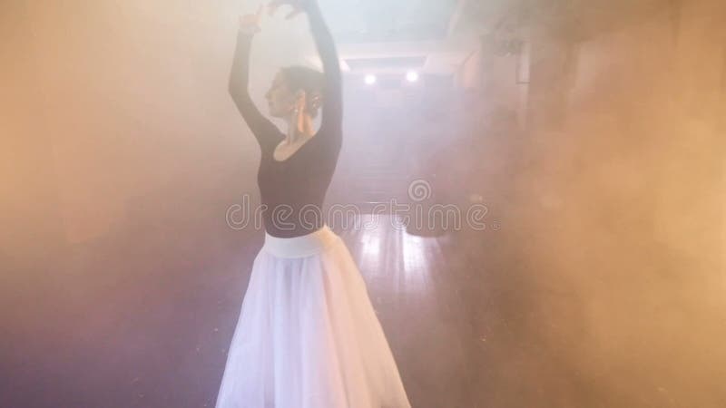 A ballerina puts her arms above her head.