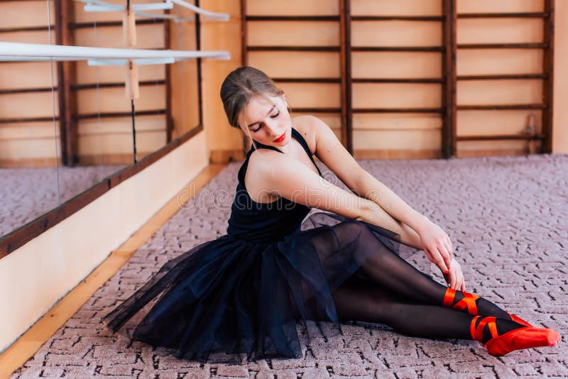 Ballerina Wearing black Tutu Doing exercise in training hall.