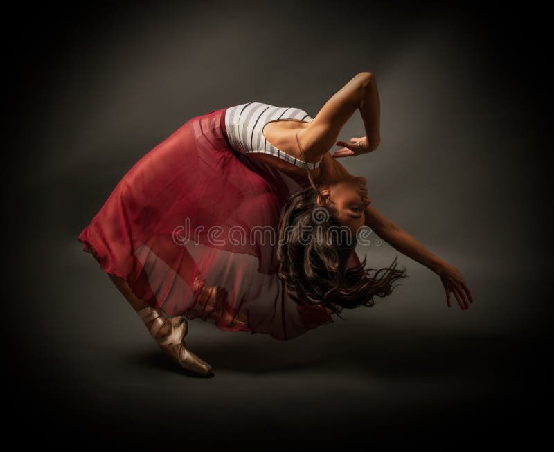 Ballerina. Young graceful woman ballet dancer, dressed in professional outfit, shoes and red weightless skirt is demonstrating dan