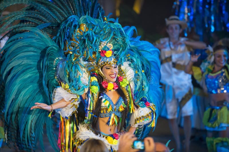 Parintis, Brazil, December 06, 2015: One attractive smiling mulatto tallanted dancer woman in bikini and carnival feather costume bright blue colors and painted face in mask, horizontal photo. Parintis, Brazil, December 06, 2015: One attractive smiling mulatto tallanted dancer woman in bikini and carnival feather costume bright blue colors and painted face in mask, horizontal photo