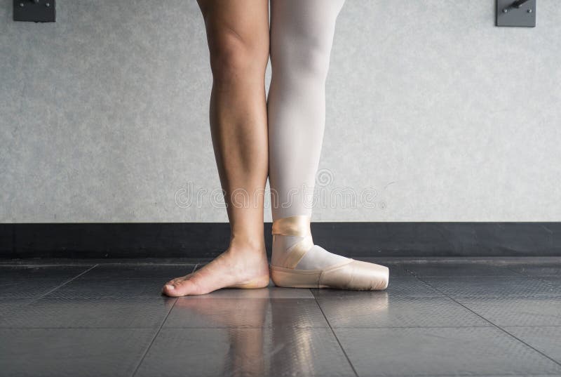 Ballerino di balletto nella prima posizione con un piede in una scarpa del pointe ed una gamba nuda fotografie stock libere da diritti Ballerino di balletto nella prima posizione con un piede in una scarpa del pointe ed una gamba nuda fotografie stock libere da diritti